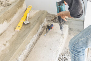 man is working with reinforce concrete stair structure modification using hand drill
