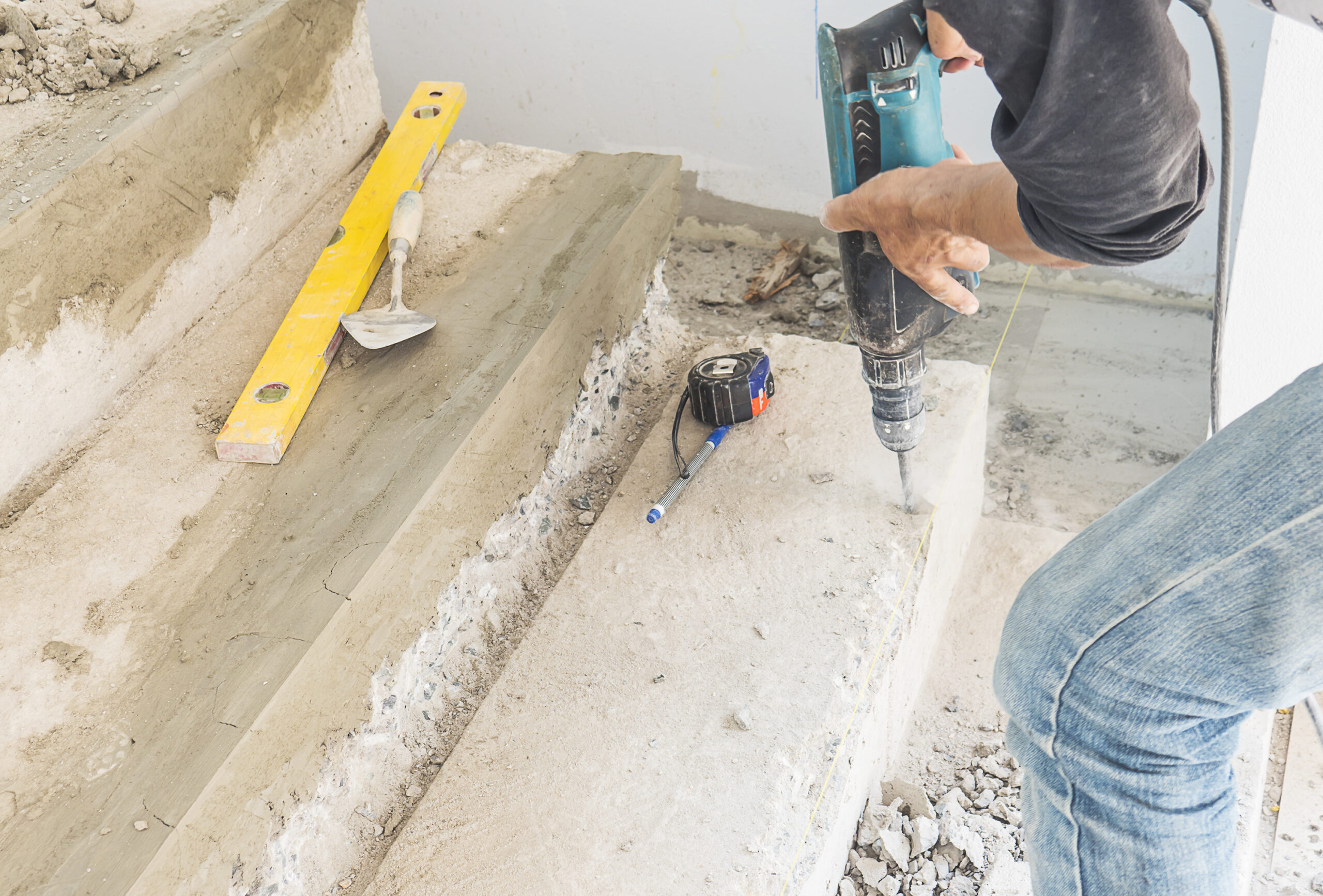 man is working with reinforce concrete stair structure modification using hand drill